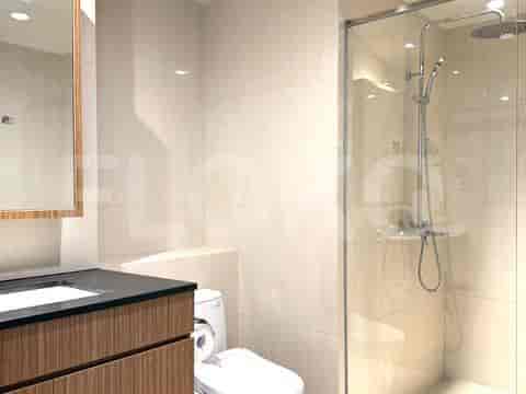 Kamar mandi modern dengan meja rias, toilet, dan pancuran kaca.
