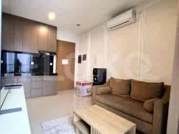 A living area with a brown sofa, coffee table, and a small kitchenette.
