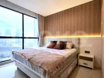 A bedroom with a large bed, bedside table, and a window with city views.