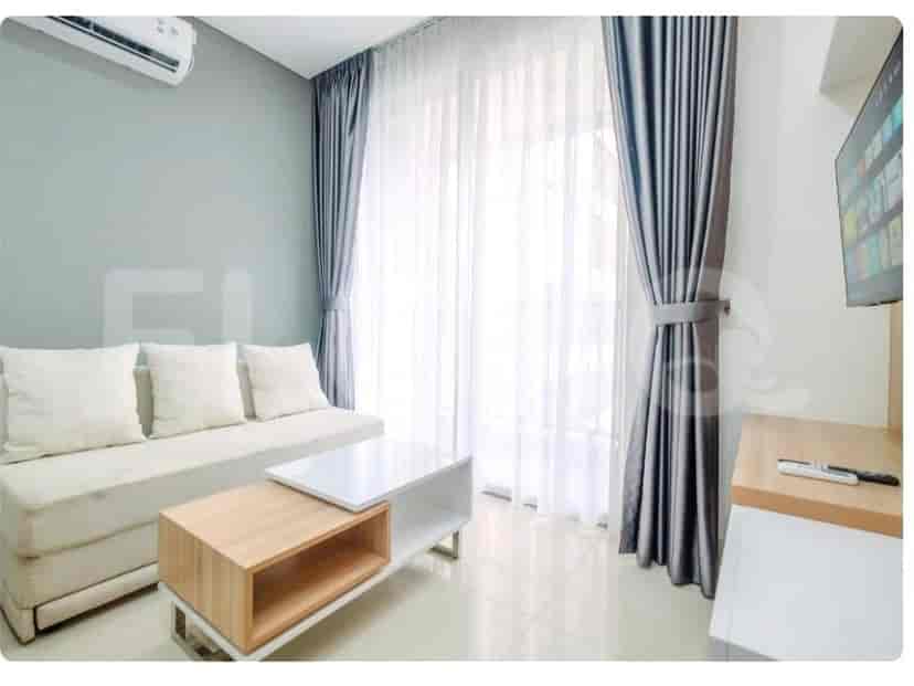 A compact living room with a light-colored sofa, a modern coffee table, and a wall-mounted TV.