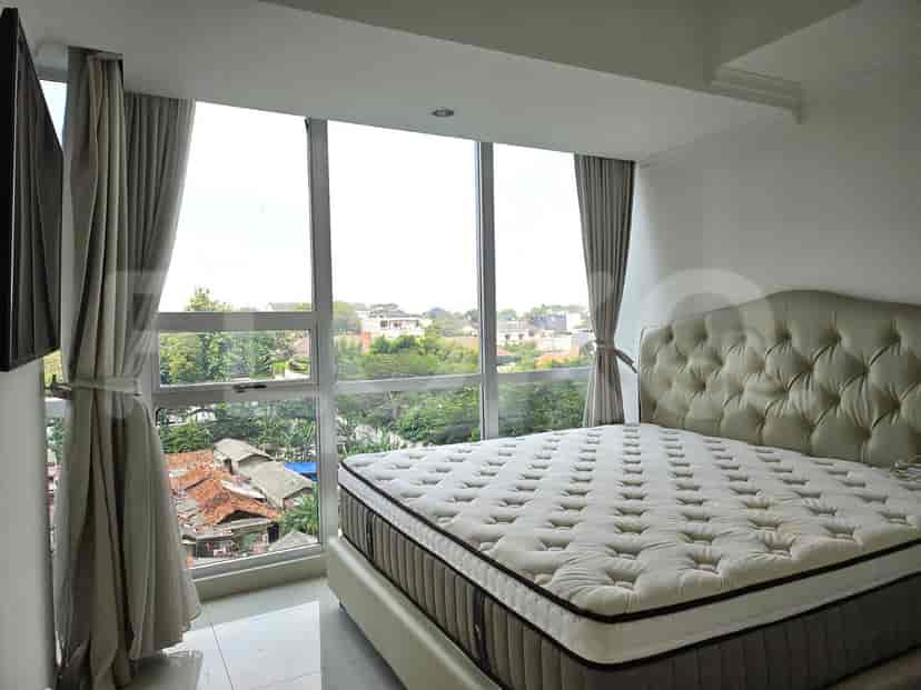 A bedroom featuring a large tufted headboard bed, floor-to-ceiling windows, and light-colored curtains.