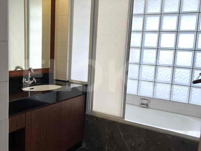 A bathroom with a bathtub, a sink, a vanity, and a glass block window.