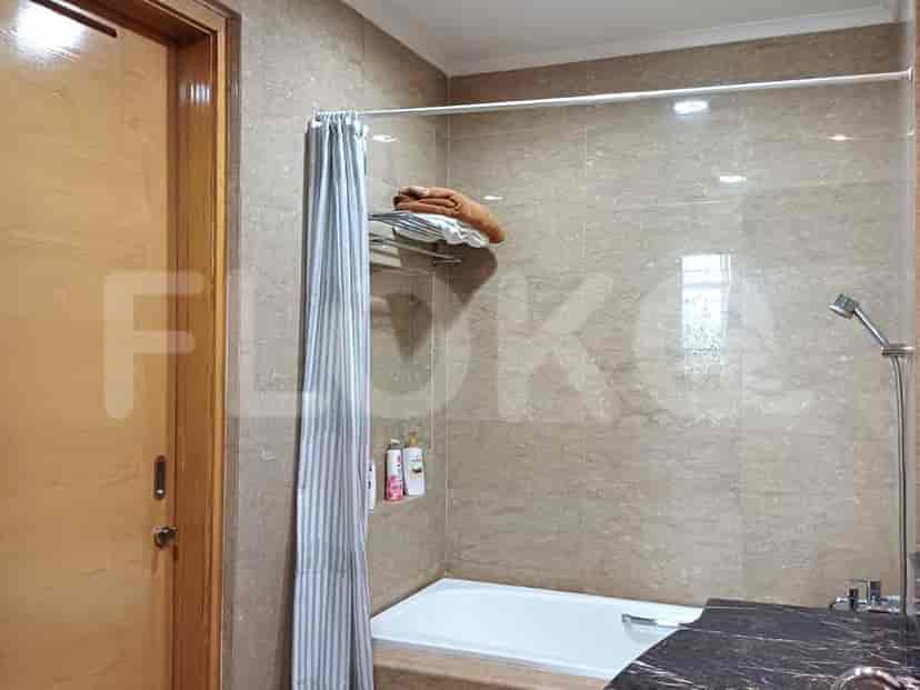 Sebuah kamar mandi dengan bak mandi, tirai pancuran, dan dinding berubin.