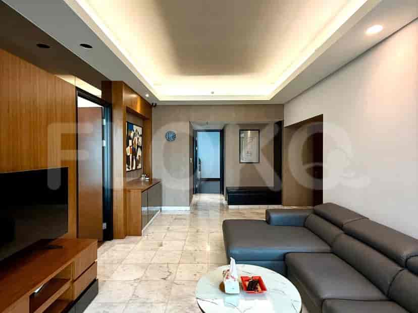 A modern living room with a large grey sectional sofa, a marble-tiled floor, and a wooden accent wall with a TV.