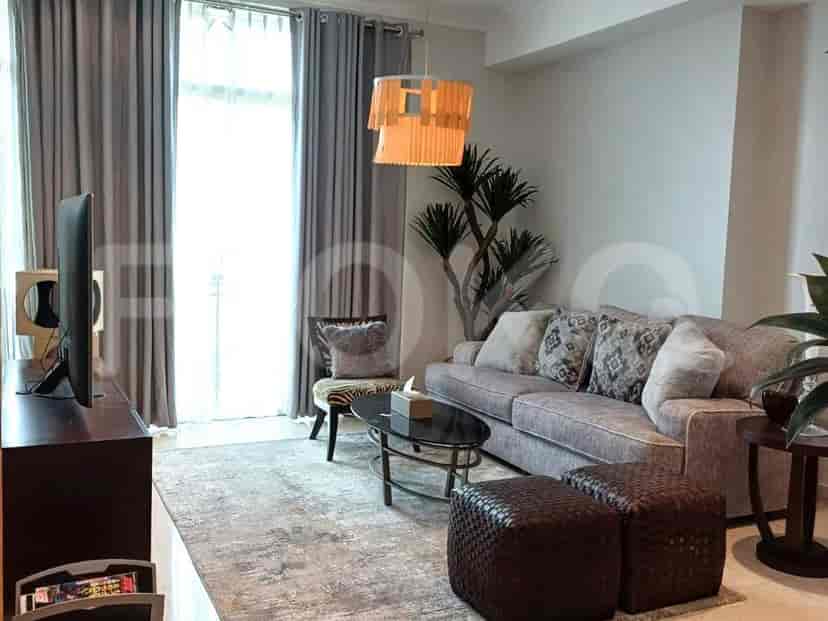 Sebuah ruang tamu modern dengan sofa, kursi aksen, meja kopi, dan televisi.