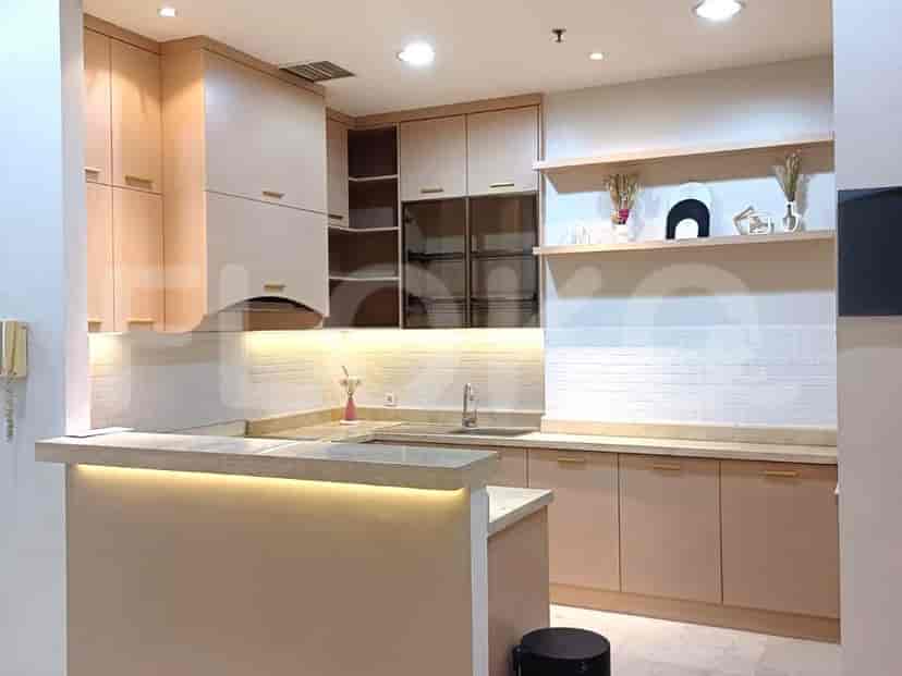 Sebuah dapur modern dengan lemari kayu terang, bar sarapan, dan backsplash ubin putih.