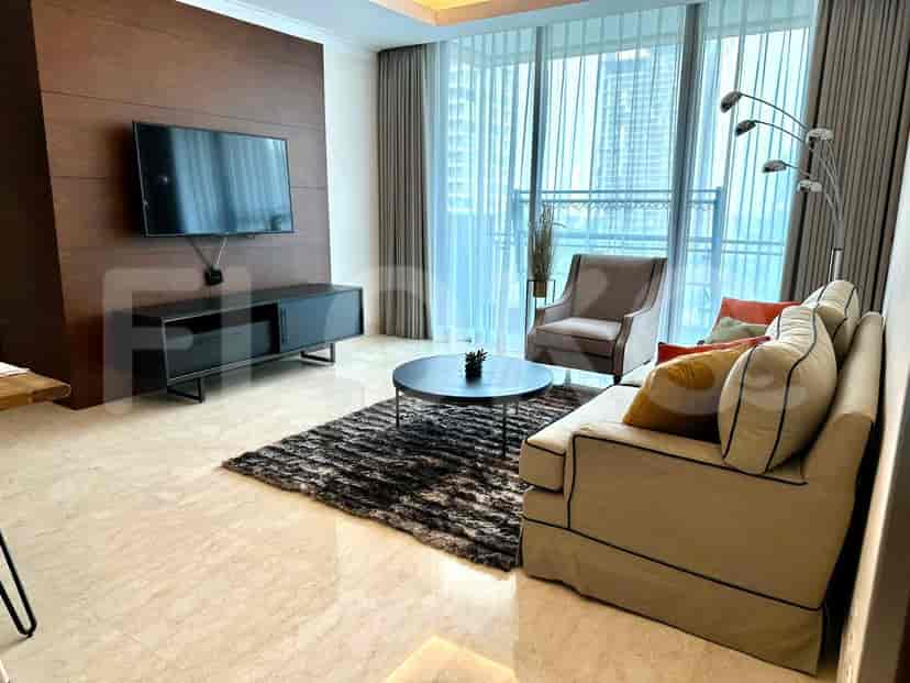 A modern living room with a beige sofa, a dark wood accent wall with a mounted TV, and a large window with sheer curtains.