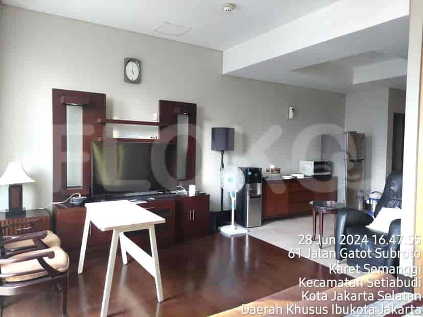 A living room with a television, a wooden table, a fan, and a water dispenser.