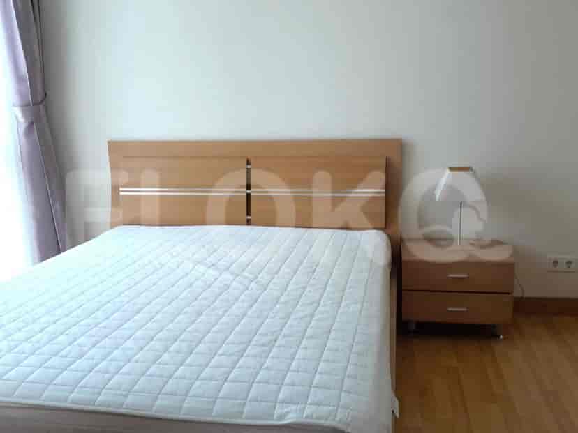 A bedroom with a queen-size bed and a light wood headboard.