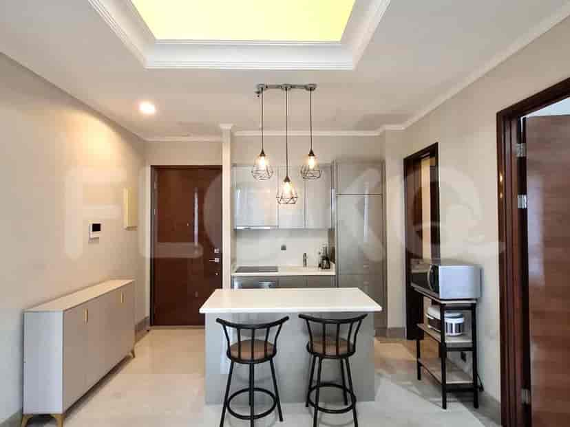 A modern kitchen with grey cabinets, a white island with bar stools, and pendant lights.