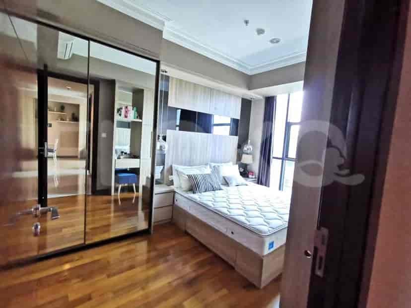 A bedroom with a queen bed, mirrored wardrobe, and wooden flooring.
