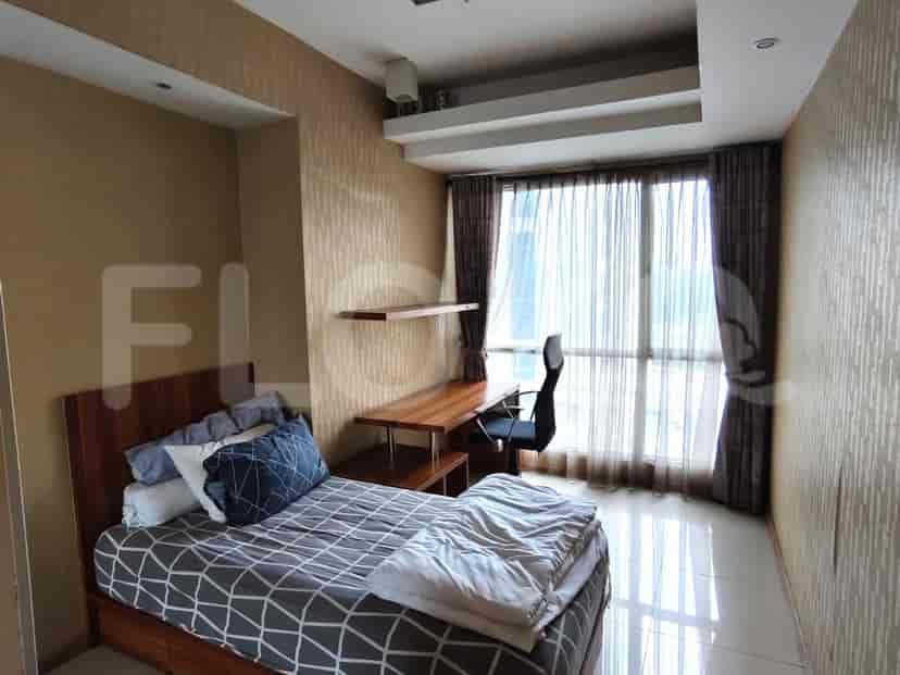 Sebuah kamar tidur dengan tempat tidur tunggal, meja kayu, dan jendela besar dengan tirai tipis dan tirai malam.