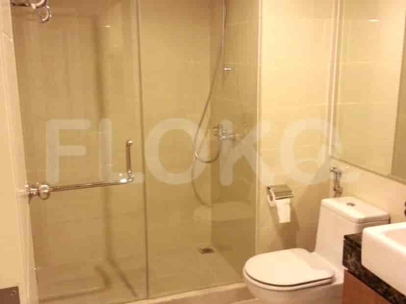 A modern bathroom with a glass-enclosed shower, toilet, and sink.