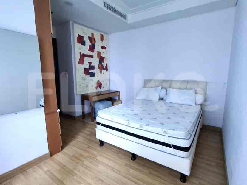 A bedroom featuring a bed, a desk with a stool, and abstract art on the wall.