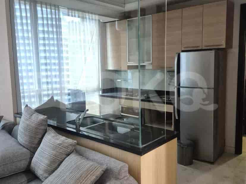 An open-concept living and kitchen area with a sofa, kitchen island with a sink, and modern appliances.