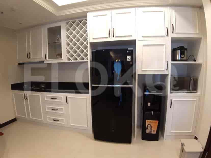 Dapur modern dengan lemari putih, meja hitam, kulkas hitam, dan peralatan tanam.