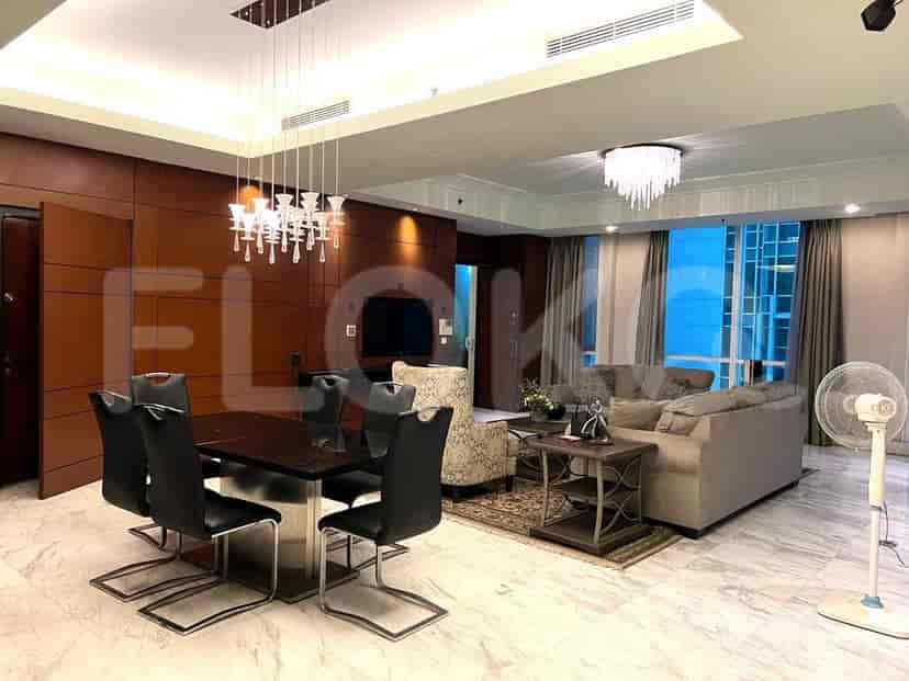 A spacious open-plan living and dining area with a large dining table, a sectional sofa, and city views from the windows.