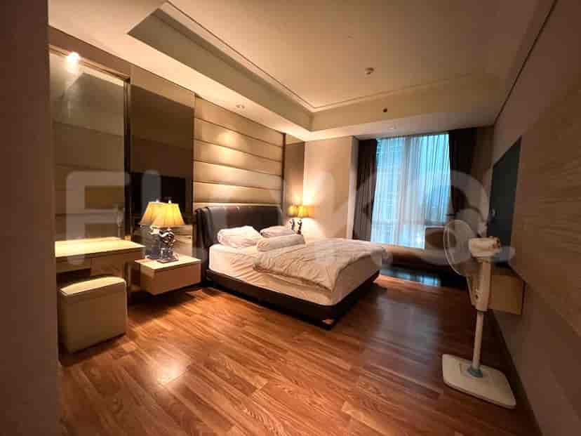 A master bedroom with a king-size bed, wooden flooring, a vanity desk, and large windows with curtains.