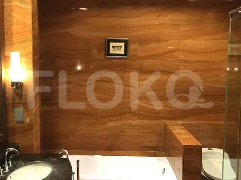 A luxurious bathroom with a bathtub, toilet, vanity, and marble walls.