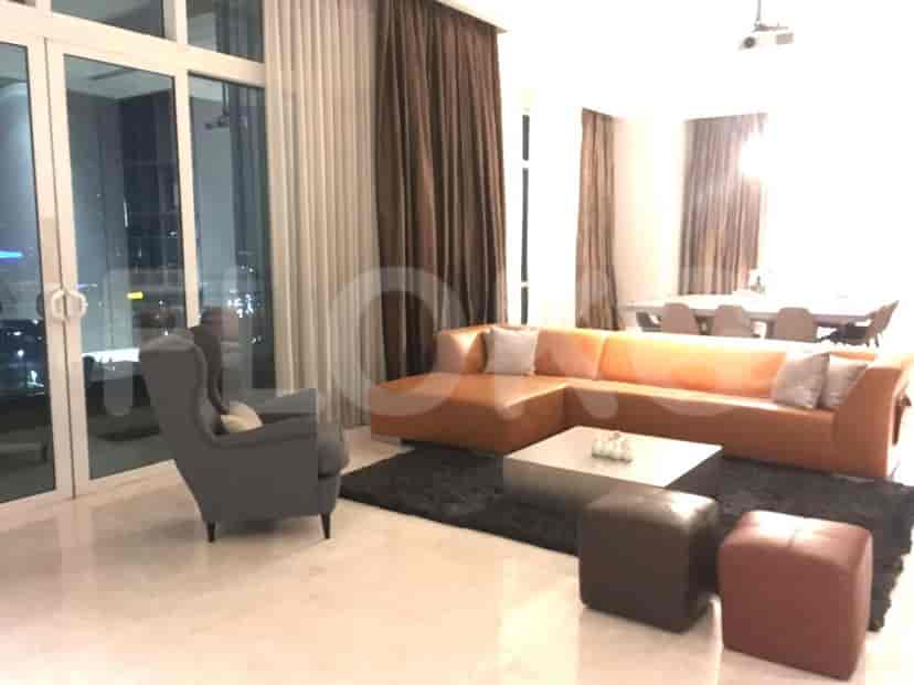 A modern living room with an L-shaped orange sofa, coffee table, and large windows with curtains.