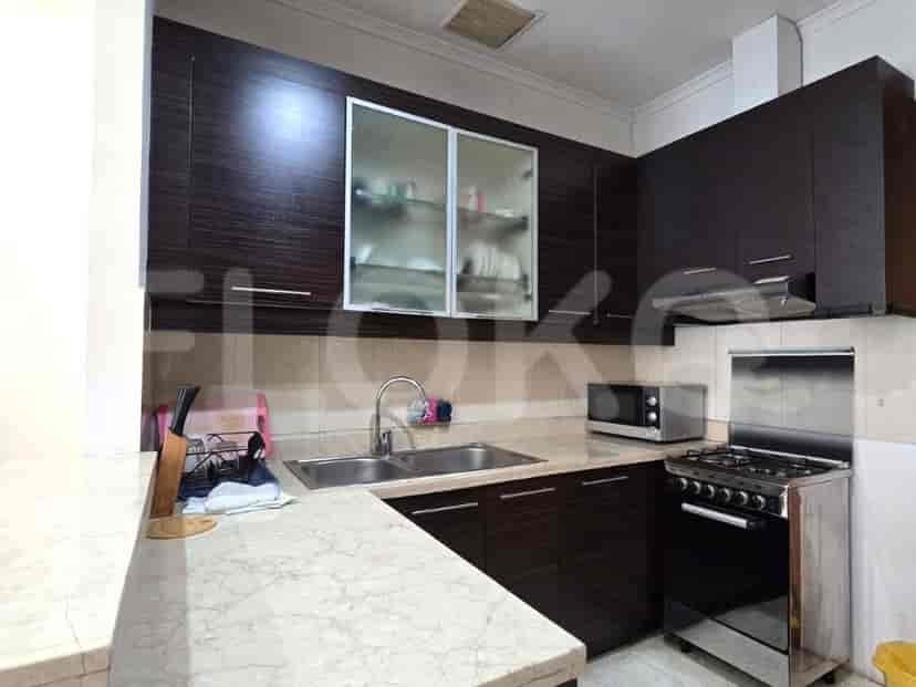 A compact kitchen with dark wood cabinets, a gas stove, microwave, and double sink.