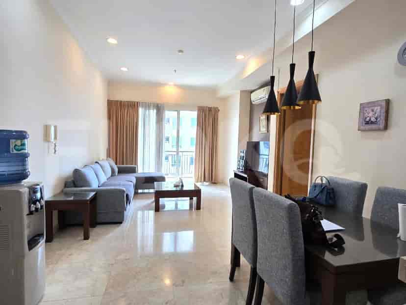 A living and dining area with an L-shaped sofa, coffee table, dining table, and water dispenser.