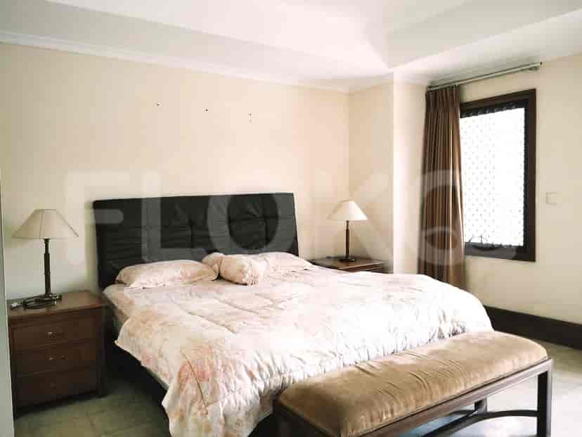 A bedroom with a large bed, nightstands, lamps, and a bench at the foot of the bed.