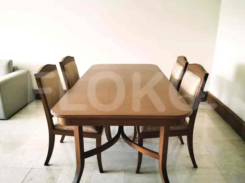 A dining table with four chairs in a room with white walls and marble flooring.