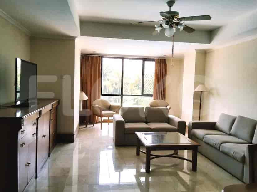 A living room with a sectional sofa, coffee table, television, and a large window with curtains.