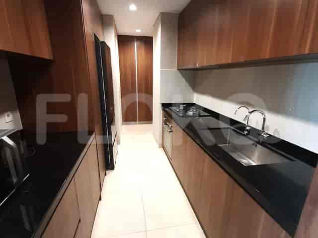 A linear kitchen with dark countertops, wooden cabinetry, and stainless steel appliances.