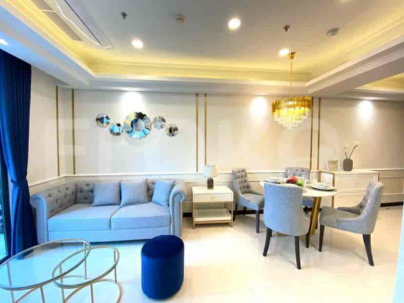 A luxurious living room with a tufted grey sofa, a modern coffee table, and a dining set.