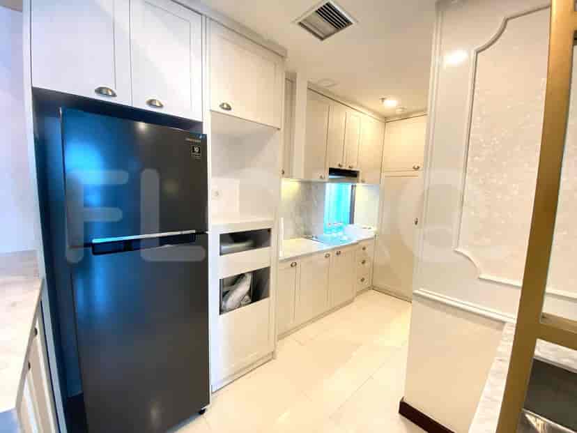 A modern white kitchen with ample cabinet space and a black refrigerator.