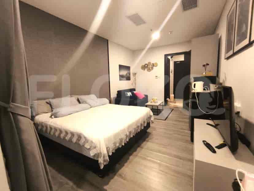 A studio apartment featuring a queen-sized bed, a small sofa, a coffee table, and a TV.