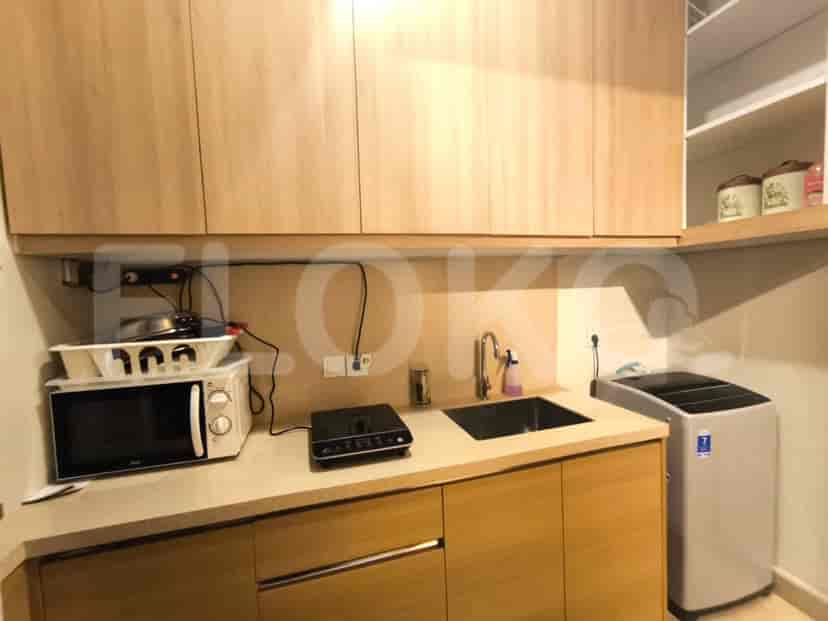 A compact kitchenette with wooden cabinets, a microwave, an induction stove, and a sink.