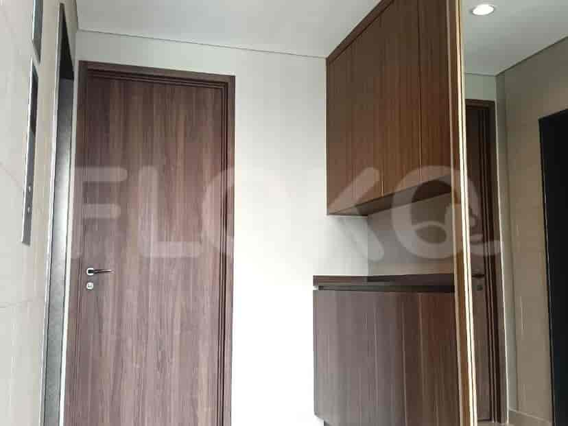A hallway with a dark wood door, tiled walls, and wooden cabinetry.