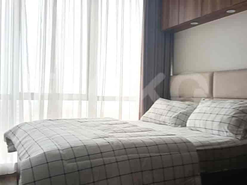 A bedroom featuring a bed with plaid bedding and a large window with sheer curtains.