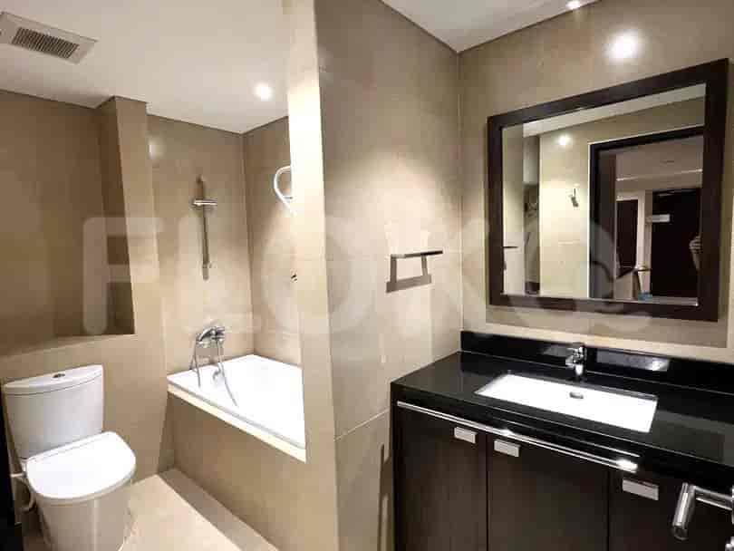 Sebuah kamar mandi modern dengan bak mandi, toilet, wastafel, dan cermin besar.