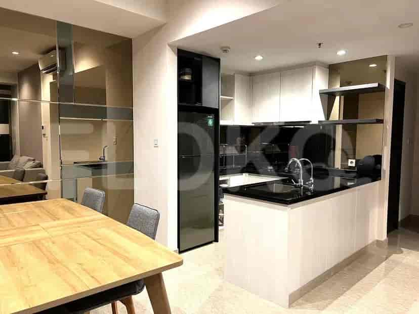 Sebuah dapur dan ruang makan terbuka dengan peralatan modern, meja makan, dan kursi, dengan dinding cermin memantulkan ruangan.