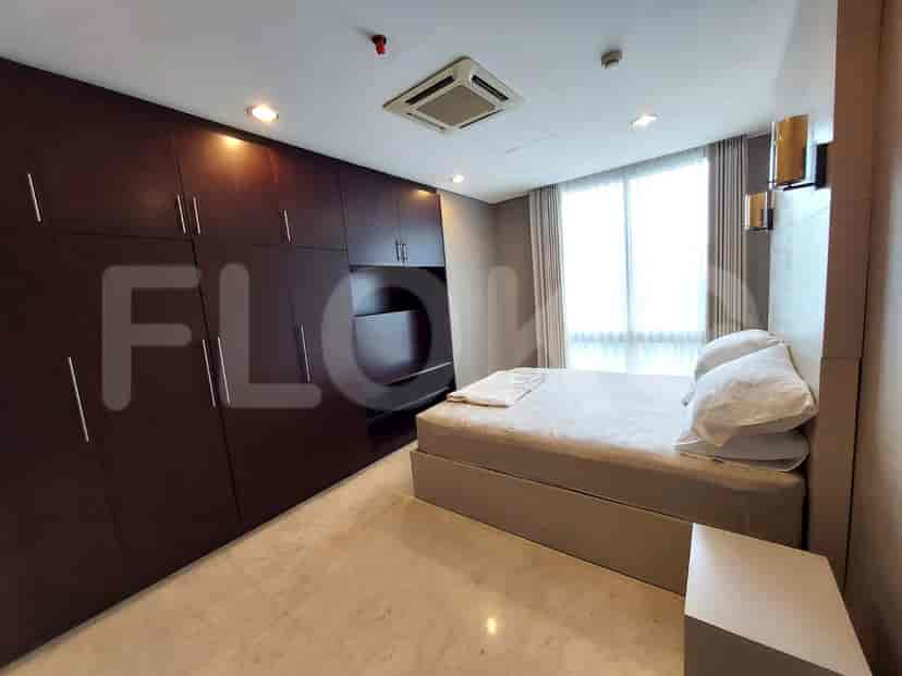 A cozy bedroom with a queen-size bed, large dark wood wardrobe, and a window with sheer curtains.