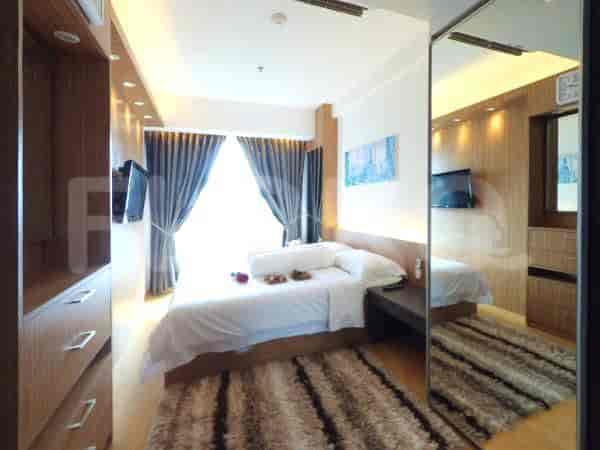 A bedroom with a queen-size bed, large windows with curtains, and a mirrored wardrobe.