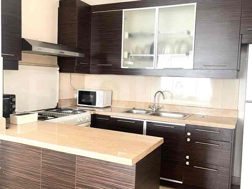 A modern kitchen with dark wood cabinets, granite countertops, stainless steel appliances, and a breakfast bar.