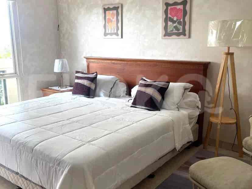 A bedroom with a large wooden headboard, queen-sized bed, nightstands, and decorative wall art.