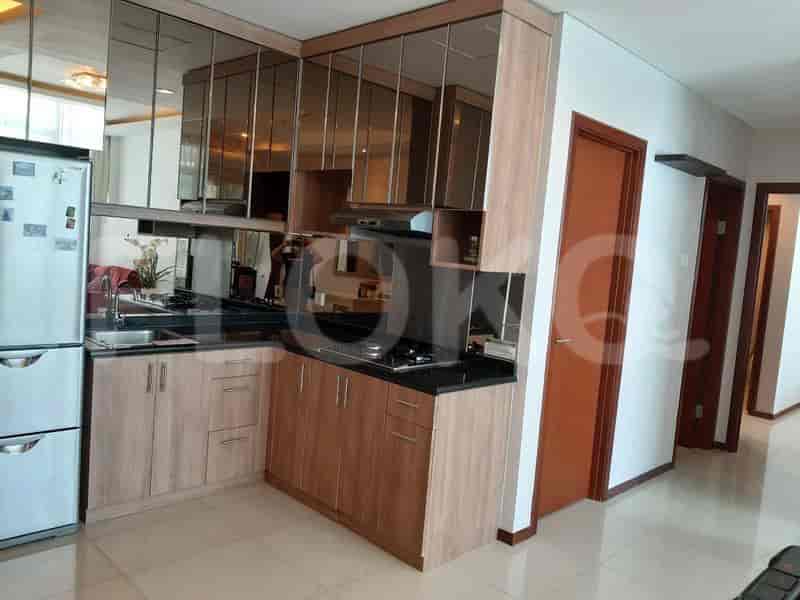 A compact kitchen with wooden cabinets, a black countertop, a gas stove, and a stainless steel refrigerator.
