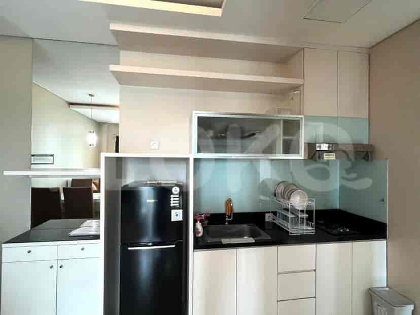 A compact kitchen with black countertops, white cabinets, a black refrigerator, and a sink.