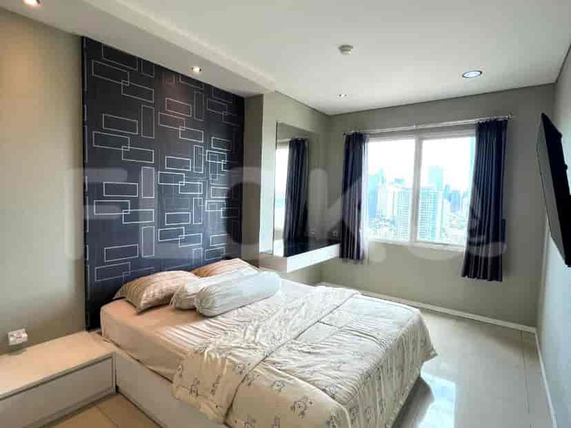 A bedroom with a queen-size bed, patterned accent wall, and a large window with a city view.