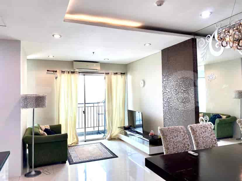 Modern living room with a green sofa, a large floor lamp, a TV console, and a balcony.