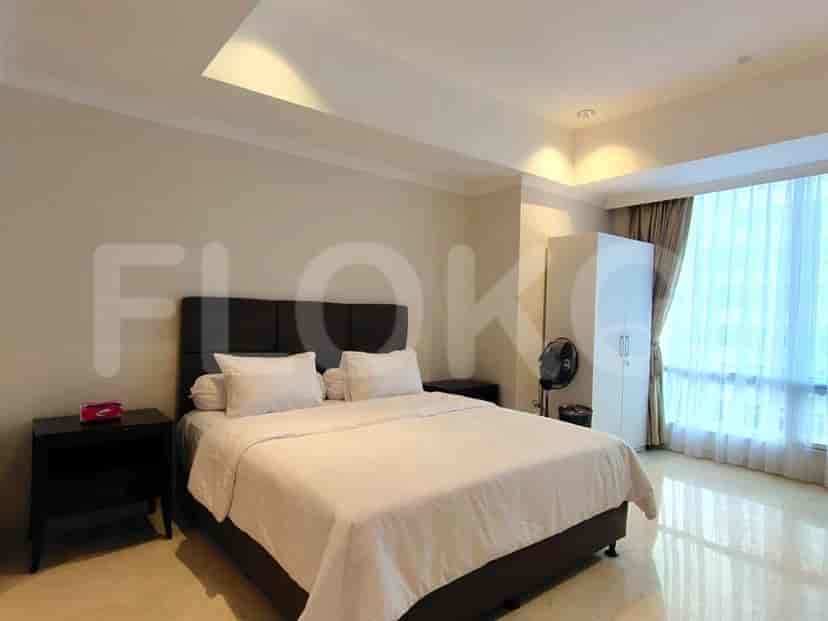 A master bedroom featuring a large bed, bedside tables, a wardrobe, and a large window with sheer curtains.