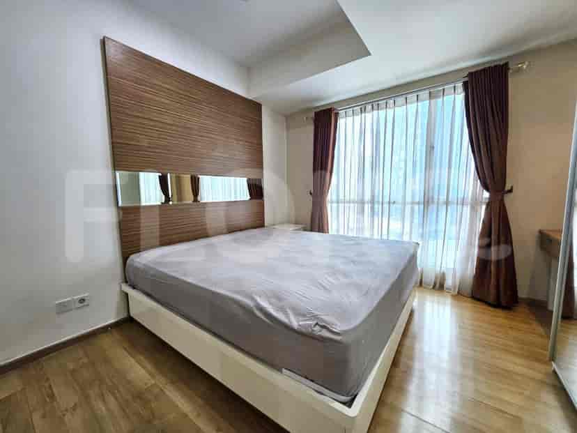 A bedroom with a large bed, wooden headboard with mirror inserts, and floor-to-ceiling windows.