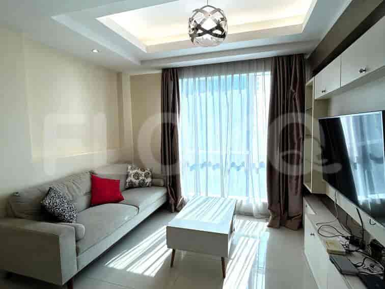 Modern living room with a grey sofa, white coffee table, wall-mounted TV, and large window with curtains.