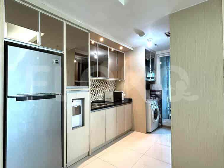 A modern kitchen with stainless steel refrigerator, built-in cabinets, sink, microwave, and washing machine.